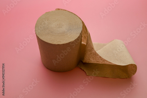 Obraz na płótnie ​A roll of eco-friendly brown recycled toilet paper is placed on a vibrant pink background