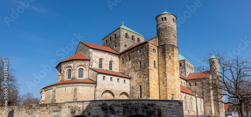 St. Michael's Church in Hildesheim, Germany. Romanesque UNESCO World Heritage site exterior with Ottonian architecture towers and sandstone walls under a clear blue summer sky.