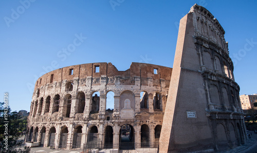 Photography Colosseum in Rome under a bright blue sky.