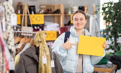 Foto Teenage girl in a clothing store holds a yellow poster with space for text