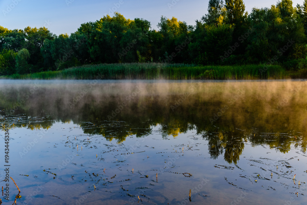 Fototapeta premium Fog above the water surface. Sunrise at river