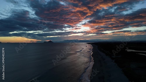 Drone aerial view of dramatic ocean coastline and sandy beach at sunset, New Zealand