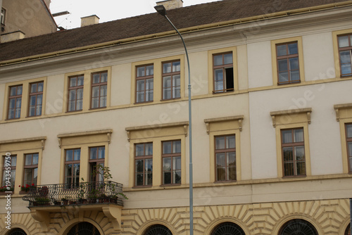 Фотография Arched ground floor with balcony above, urban details and planted railing, warm