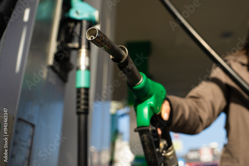 Foto Hand holding gasoline nozzle at fuel station close-up