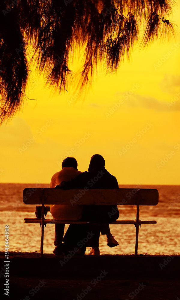 Obraz premium Silhouette seniors couple waiting for the colourfull sunset on the bench near the Indian Ocean, Mauritius, Africa