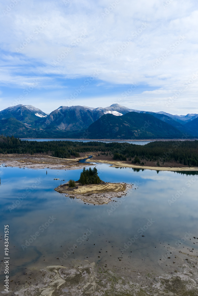 Obraz premium Small Island and Lake Reflection With Mountain Range and Forested Shoreline in BC Canada