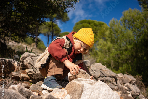 Cuadro en lienzo Young boy exploring rocky terrain during mountain hike, carefully touching stone