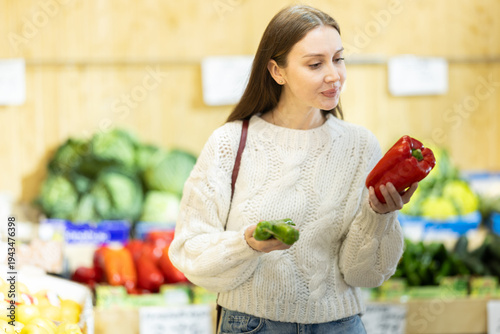 Bilde på lerret Girl shopping, examine vegetable in store and buy elect pepper