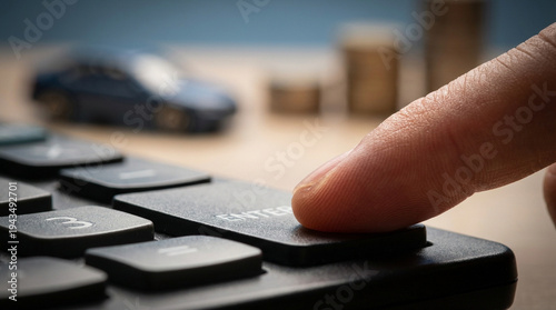 Finger pressing enter button on calculator with blurred car and coins