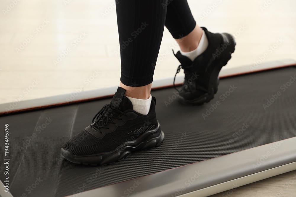 Obraz premium Sporty woman training on treadmill at home, closeup