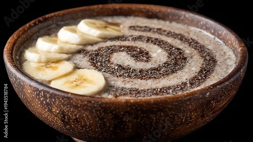 Delicious Healthy Breakfast Oatmeal with Banana Slices and Chia Seeds in Rustic Wooden Bowl.