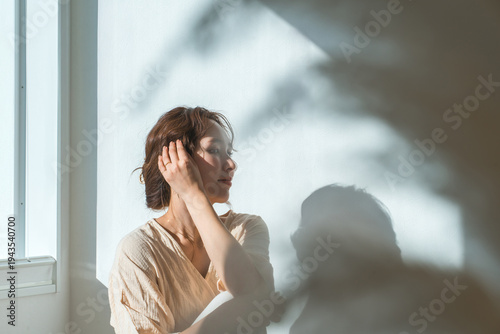 Canvastavla A woman by the window in the setting sun (model, fashion, light, shadow)