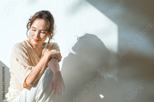 Bild auf Leinwand A woman by the window in the setting sun (model, fashion, light, shadow)