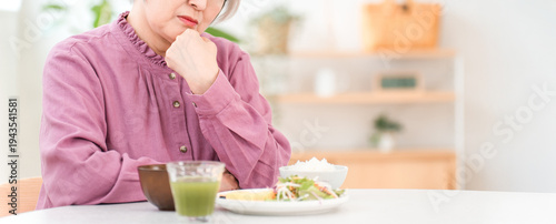 Tableau sur toile A gray-haired senior woman eating in the dining room at home