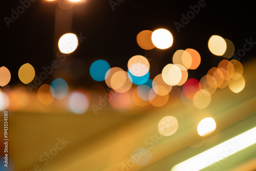 Out-of-focus city lights create a colorful abstract bokeh pattern against a dark background. Suitable for backgrounds, design projects, or creative visual concepts.