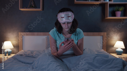 Obraz na płótnie Woman Using Smartphone in Bed Wearing Sleep Mask in Bedroom, have fun and enjoy