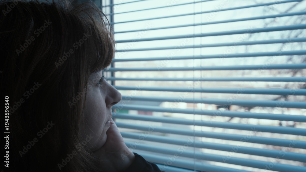 Fototapeta premium happy Woman Looking Outside Through Window Blinds in Thoughtful Mood in the evening
