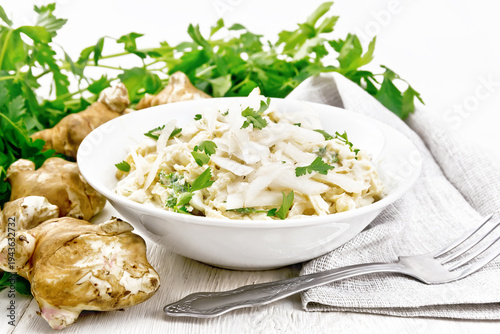 Salad of Jerusalem artichoke and eggs in plate on white wooden board