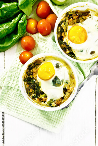 Scrambled eggs with spinach in bowl on light board top