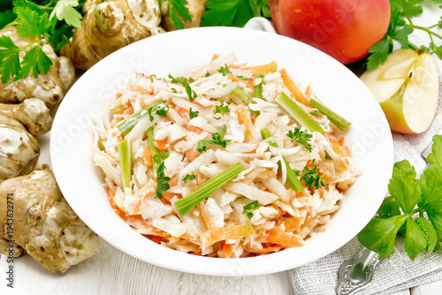 Salad of Jerusalem artichoke and apple in plate on white board