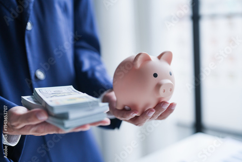 Saving money. hand putting money into pink piggy bank making investments or strategy for personal savings