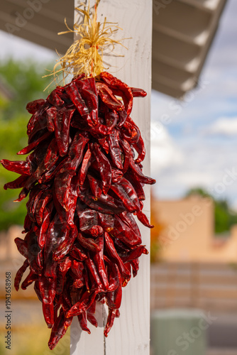 ristra of chili peppers or string if chillies or red peppers hung or hanging outside an exterior front porch of a home in new mexico traditional outdoor food home decor or way of drying chilli peppers