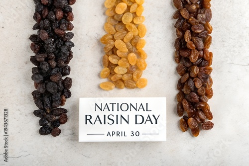 Celebrating national raisin day on april thirtieth with three distinct varieties of dried grapes displayed vertically on a light textured surface for a healthy food holiday celebration.