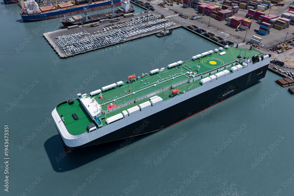 Obraz premium Aerial view of a huge Ro-Ro vehicle transport ship in the process of unloading on maritime port platforms