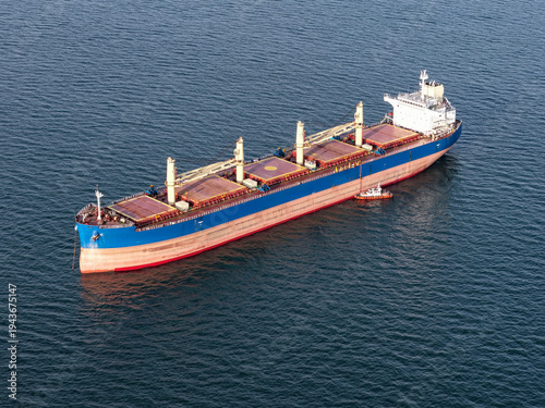 Aerial view of a huge grain transport ship docking in a bay next to a seaport