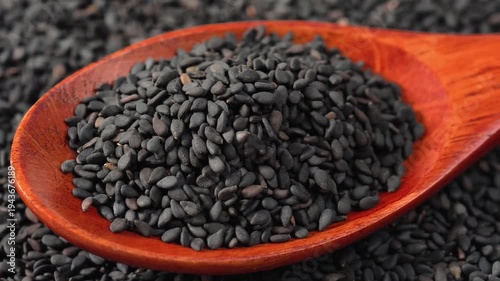 A wooden scoop filled with tiny, aromatic black sesame seeds