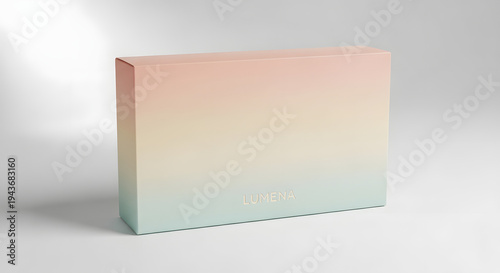 A rectangular box with a soft gradient of pink, yellow, and teal, featuring the embossed word LUMENA.