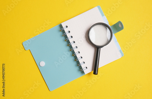 Notepad with a magnifying glass on a yellow background