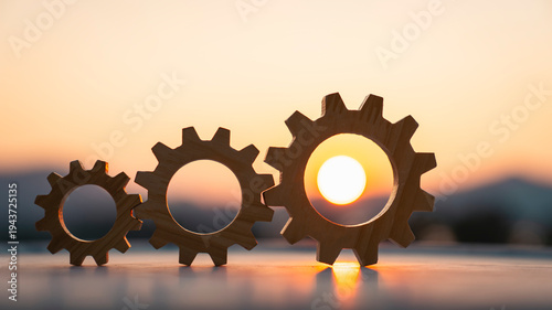 Row of gears from small to large with bright sunlight on biggest gear for systematic teamwork and efficient business success concept. Growth process and industrial mechanical solution.
