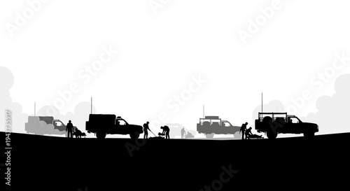 Silhouette of people working on vehicles in a desert landscape