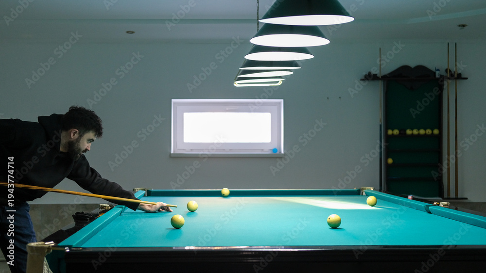 Fototapeta premium Focused young man playing Russian billiards in game room.