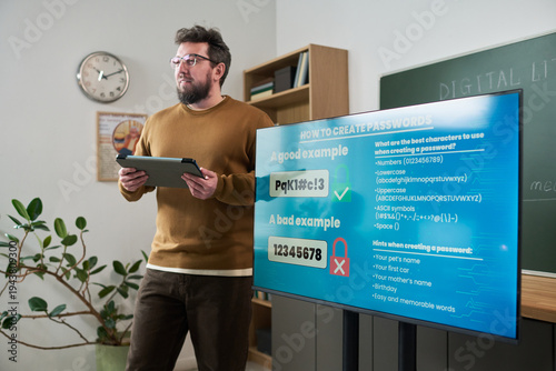 Fotografía Middle aged Caucasian man standing in classroom holding digital tablet, presenti