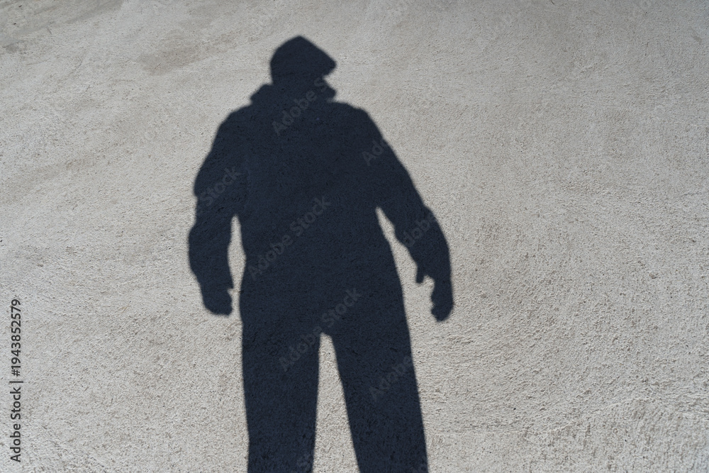 Fototapeta premium Dark shadow of a lonely person on the ground in the street. Stranger. Anxiety, depression, loneliness, fear concept. 