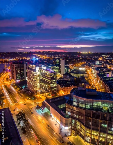 Aerial cityscape at dusk with lit buildings and roads