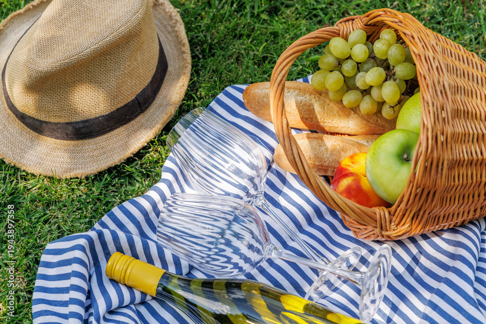 Fototapeta premium Picnic with wine, fruits, and baguette on a green meadow