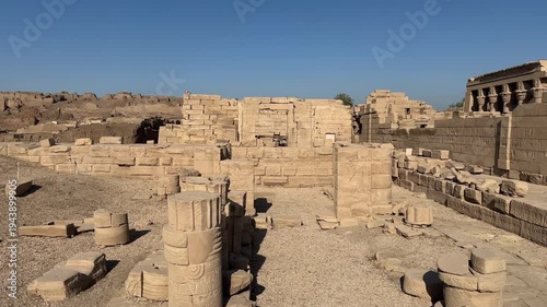 Wide panoramic shot of the archaeological ruins and scattered stone blocks at the Dendera Temple complex in Egypt with the main temple in the background