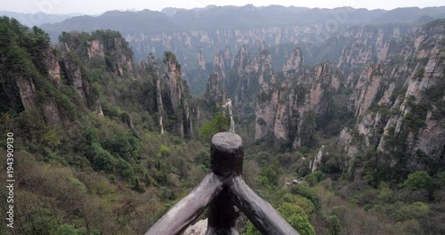 Camera moving forward on observation deck, passing over safety railings to reveal majestic panorama of unique quartz sandstone pillars and deep canyons at West Sea scenic spot at Zhangjiajie