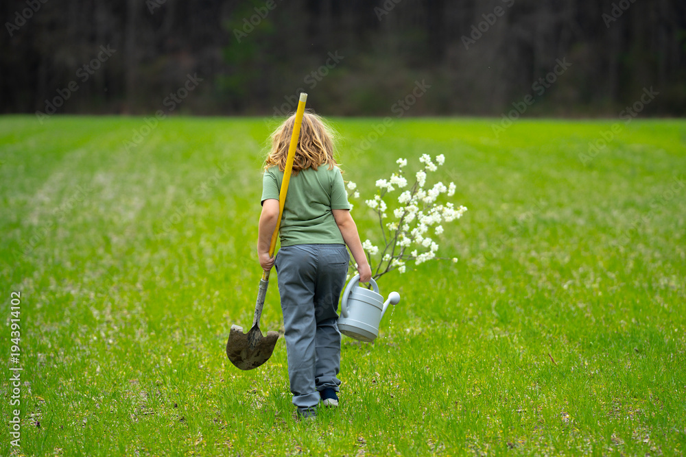 Fototapeta premium Child planting tree outdoors. Spring activity of plant trees. Kid work with shovel and watering can. Kid plant fruit tree. Gardening kids. Kid growth plant and care for tree. Rural kids life. Little