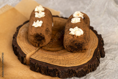 a black potato cake lies on a serving board and paper, a sweet classic cake made from butter and a cocoa mixed with sponge cake and cognac