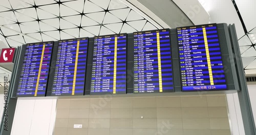 Orbiting shot of a digital flight information display system in a modern airport terminal. Real-time timetable showing international departures, gate numbers, and flight status updates