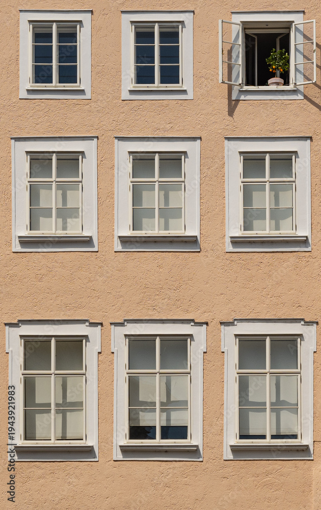 Fototapeta premium Facade of a building with symmetrically arranged wooden-framed windows. Traditional and rustic style.