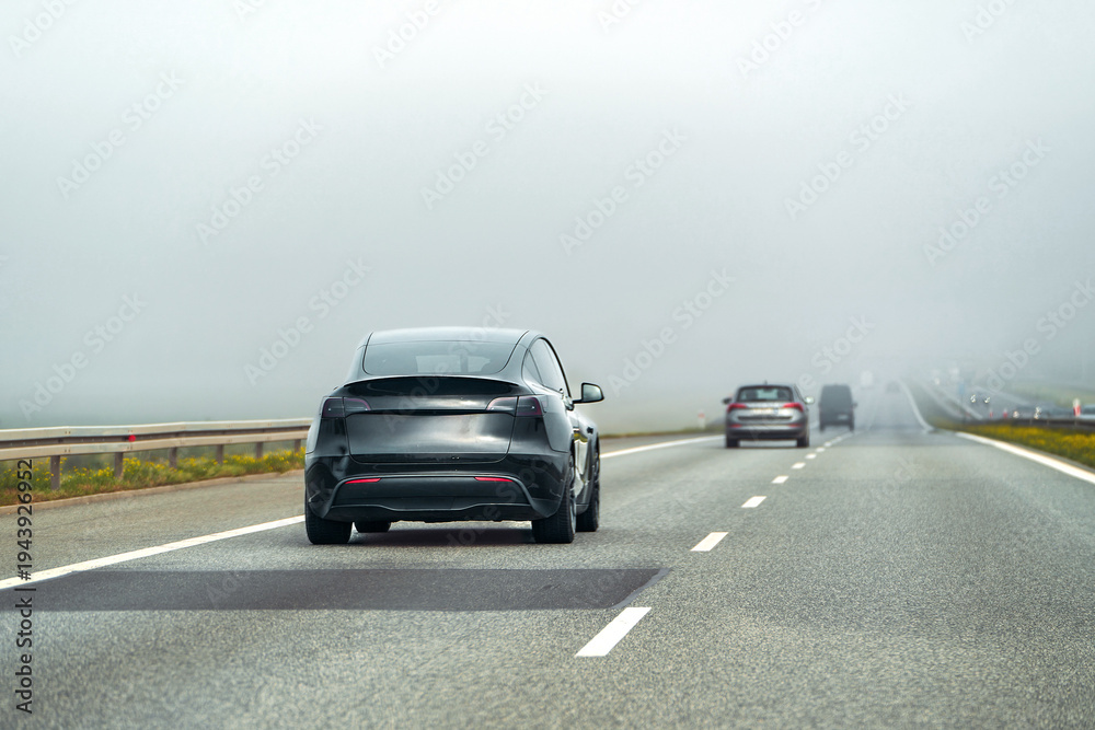 Fototapeta premium Electric SUV on quiet road surrounded by nature