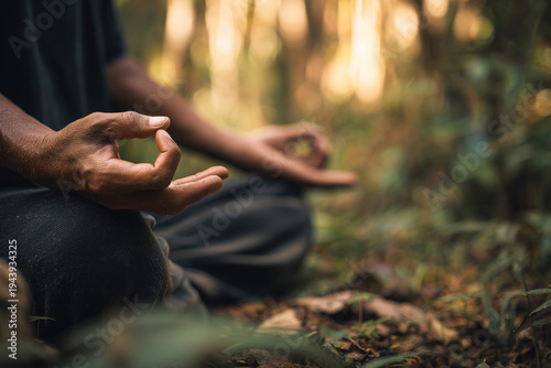 Southeast Asian man meditating in peaceful forest clearing. Nature-based mindfulness and holistic wellness. Asian man exercising meditation in nature, minfulness, mental health theme.