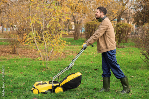 Male gardener using lawn mo...
