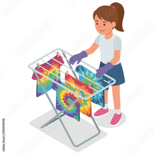 A girl is hanging colorful tie-dye shirts on a drying rack indoors.