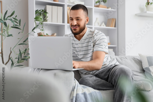 Young man using laptop to s...
